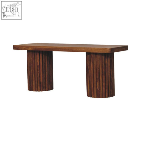 A sleek astoria fluted bench with dark brown natural mango wood and fluted cylindrical legs and a smooth top