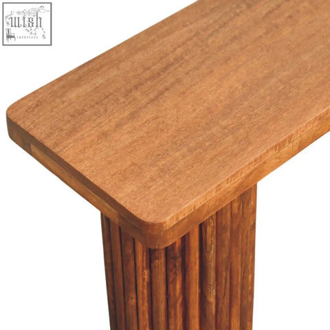 Astoria fluted bench in warm natural mango wood with a smooth polished surface and vertical slat pedestal base