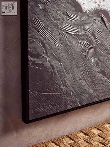 A textured gray abstract wall art with raised wavy lines in a dark frame featuring earthy tones textured design
