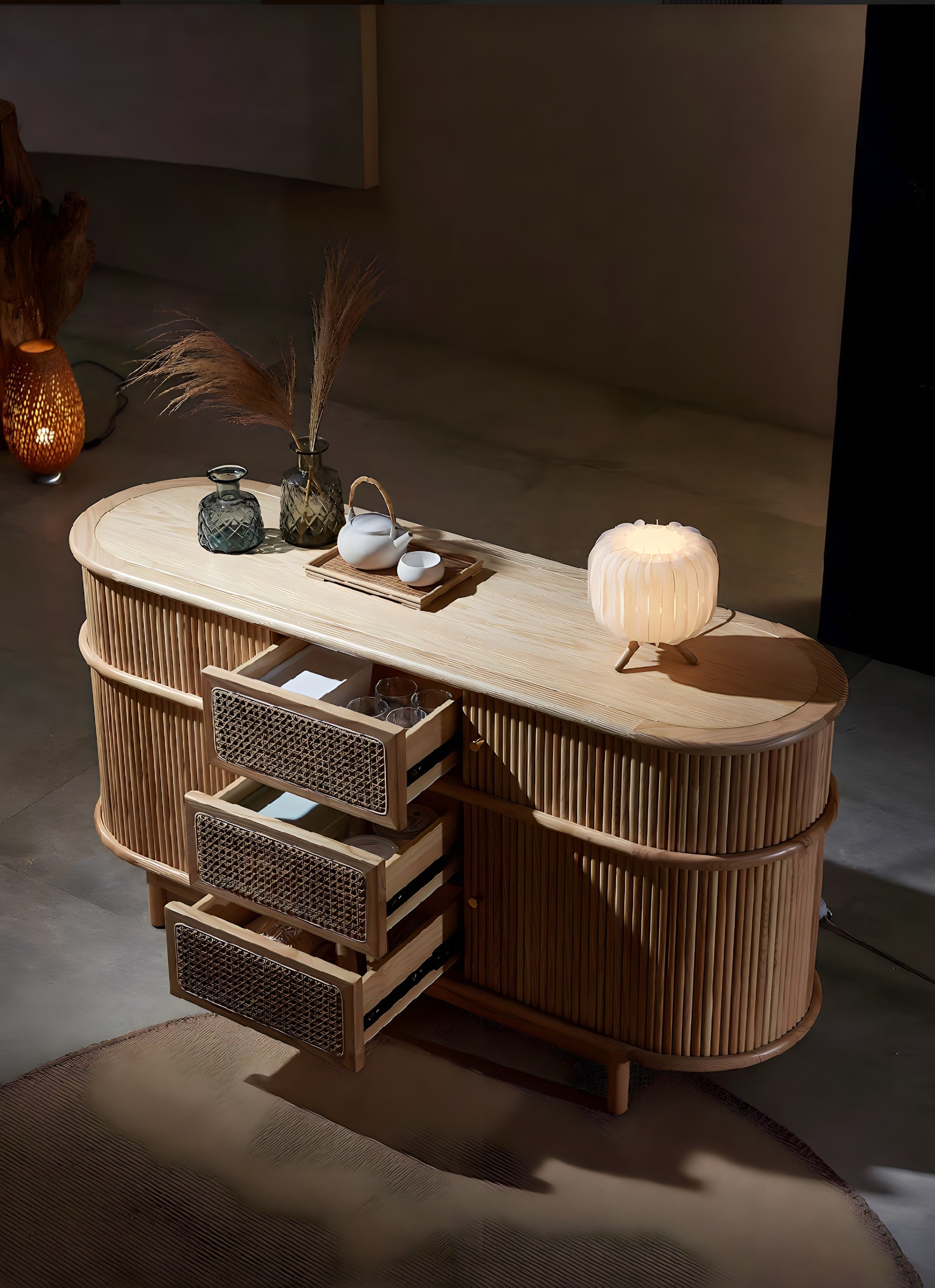 A sleek oval rattan asuka cabinet with light wood top and three open woven wicker drawers for stylish storage