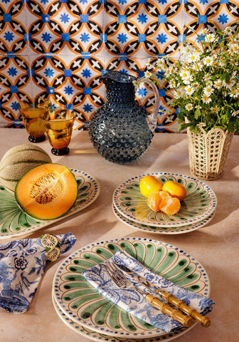 Hand-painted ceramic plates with green and blue peacock feather patterns stacked in a set from atlántico iraca scallop vase natural