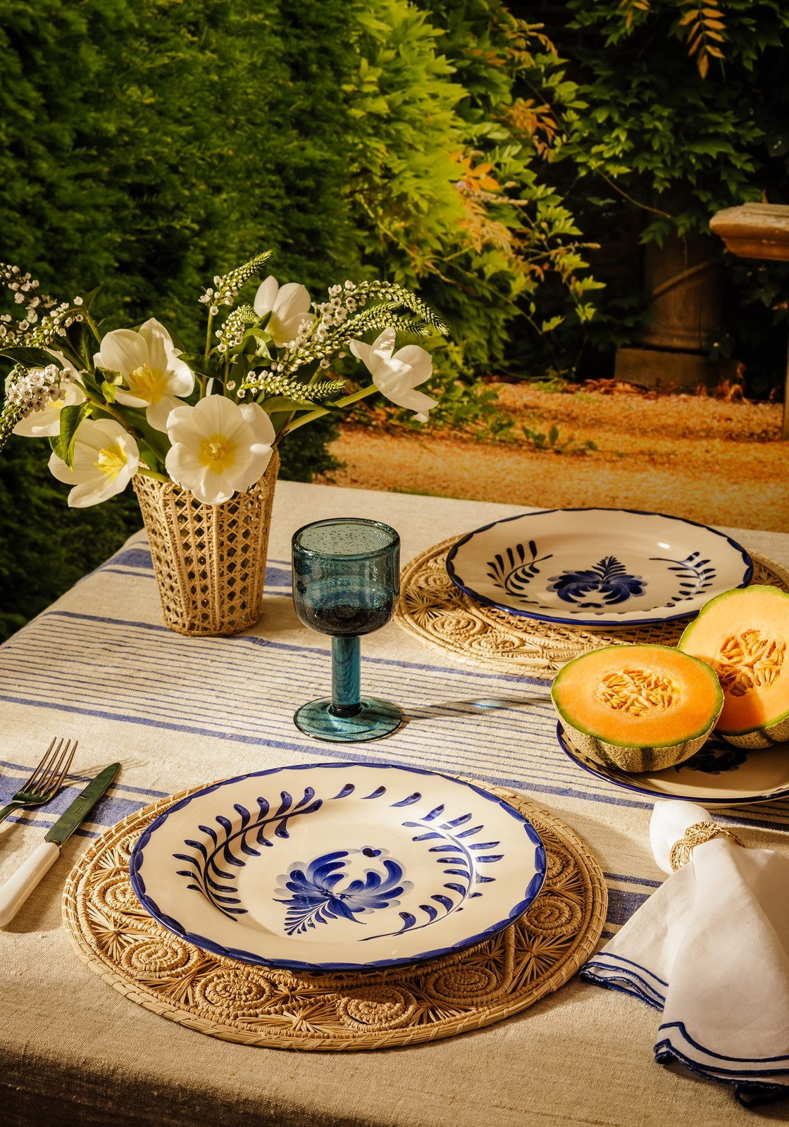 White ceramic plate with intricate blue floral and leaf patterns and a bold blue rim from atlántico iraca scallop vase natural collection