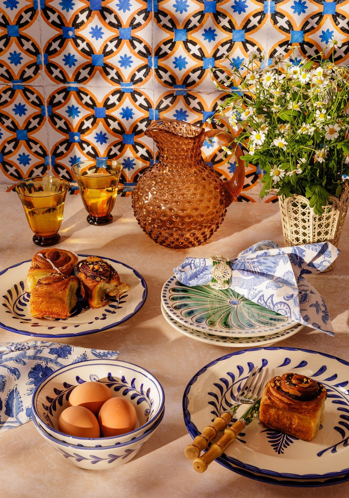 Amber textured glass pitcher with curved handle and spout paired with a green iraca woven napkin ring
