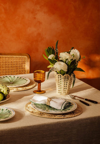 Elegant green and white ceramic plate with leaf pattern on a natural atlántico iraca woven napkin ring and placemat