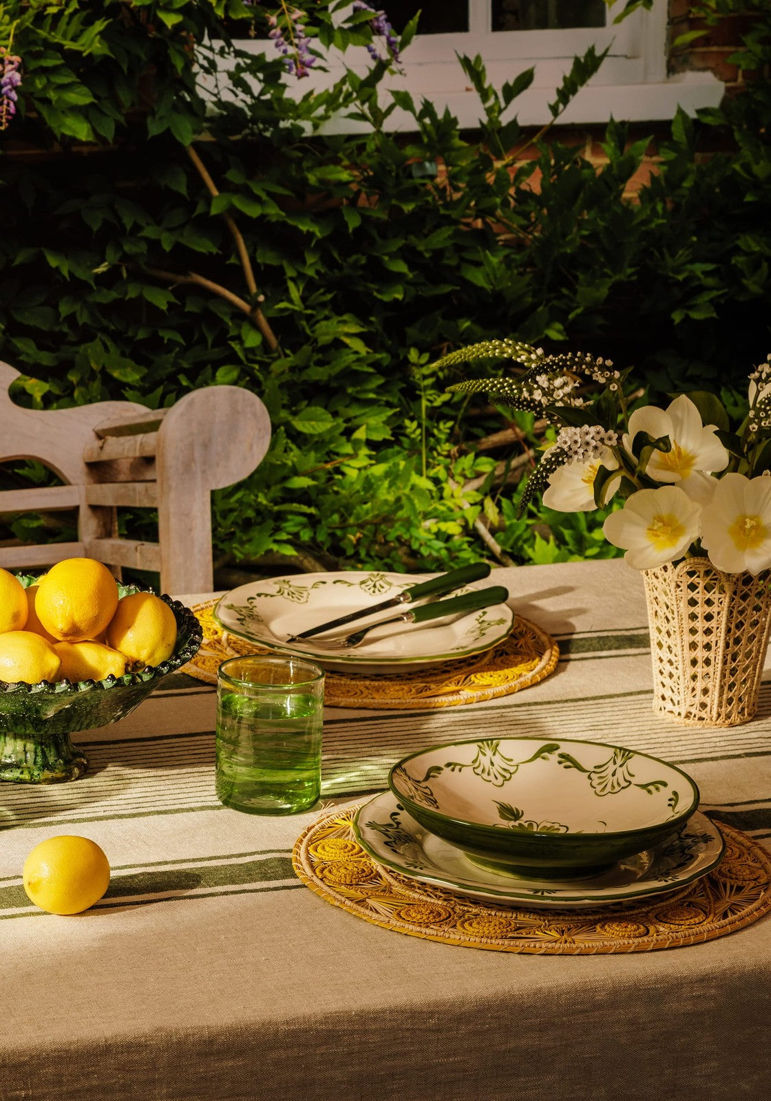 Green and white ceramic dinnerware with floral patterns on yellow atlántico iraca woven placemats