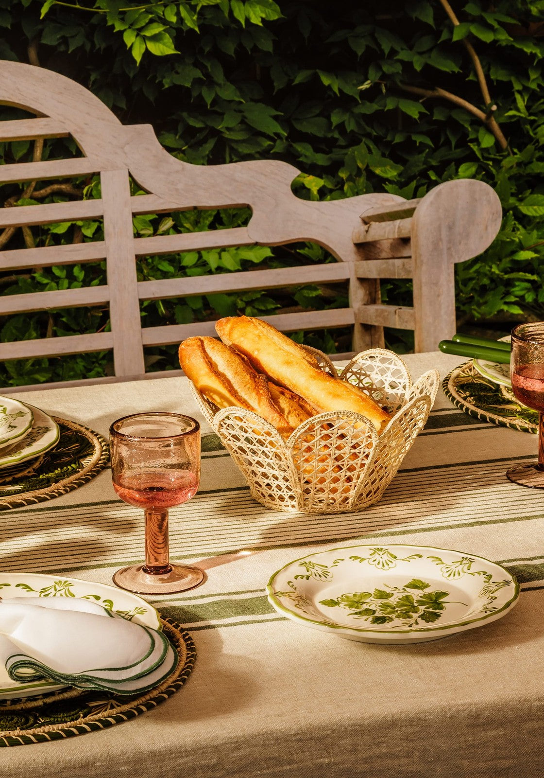 A cream-colored natural iraca woven atlántico scallop basket with lace pattern holding golden-brown baguettes