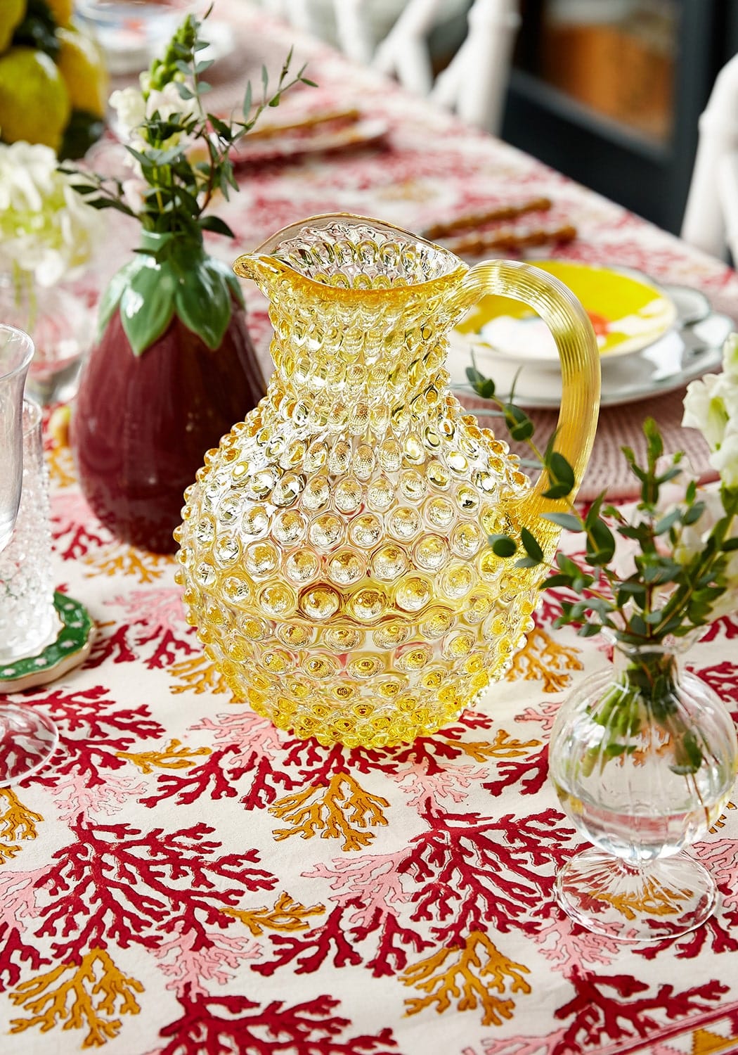 A translucent yellow glass aubergine bud vase with a textured bubble surface and a curved handle