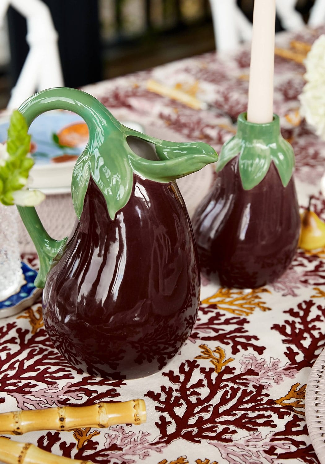 Deep maroon ceramic aubergine dream candle holder shaped like an eggplant with a glossy finish and leafy green handle