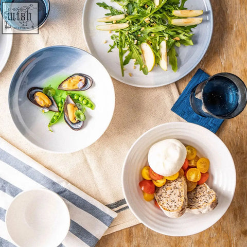 White ceramic aurora dinner set bowls with textured rims holding mussels arugula salad and burrata cheese dining set