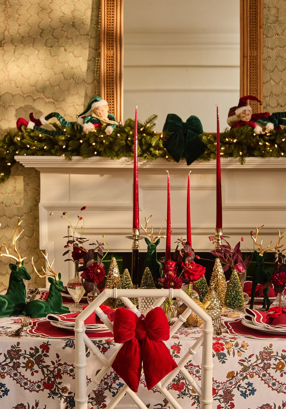 A festive white bamboo chair with a plush red velvet bow next to aurora medium slender red taper candles
