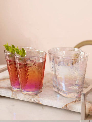 Four clear lustre glass tumblers with hammered finish from the aurora set on a marble tray