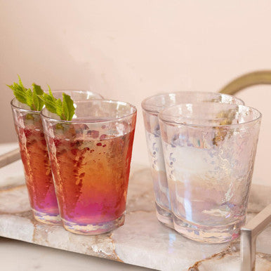 Two clear lustre glass tumblers with a subtle hammered finish from the aurora set sit on a marble tray
