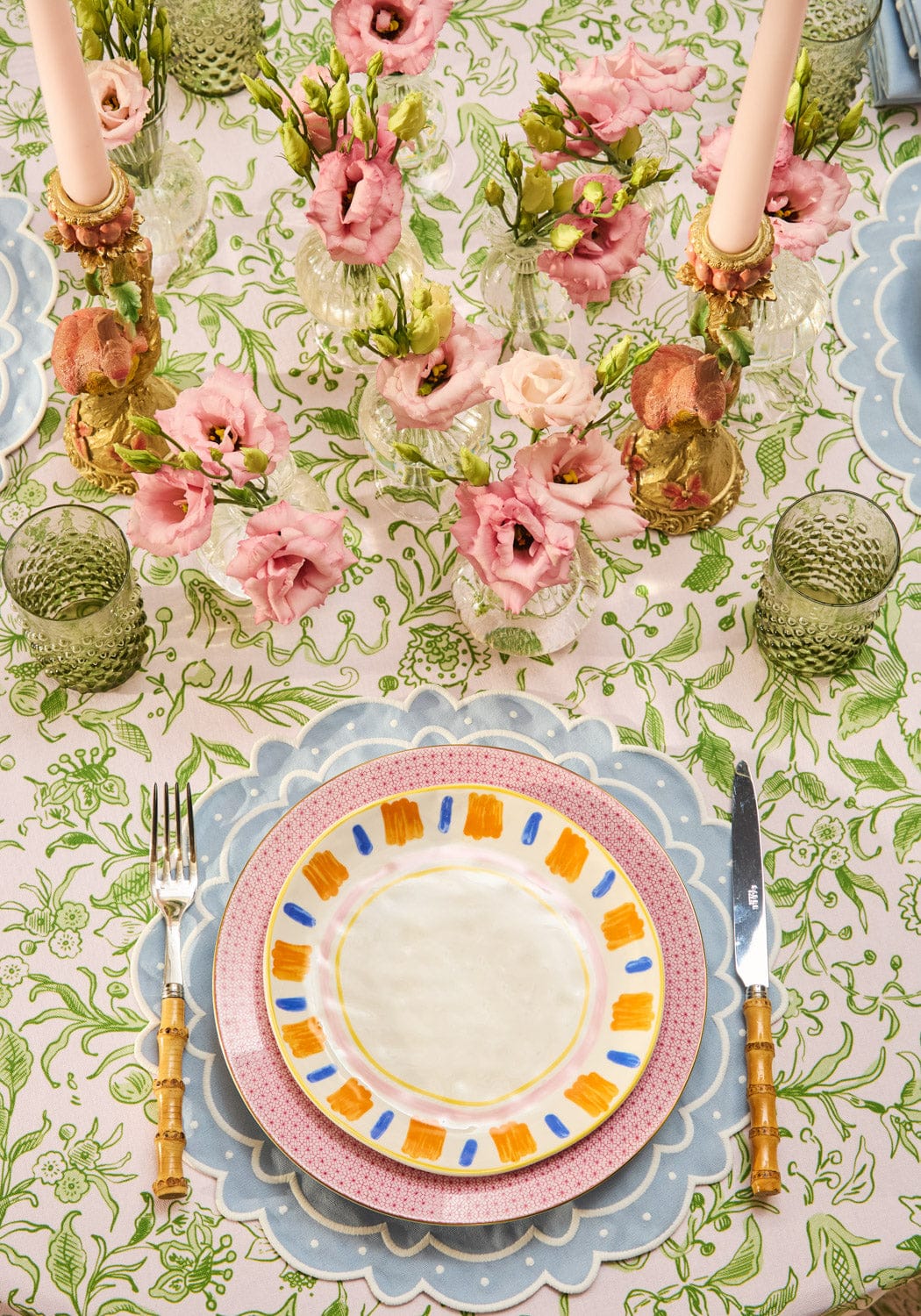 A vibrant pink and blue patterned ceramic plate on a light blue aurora set of 4 placemats with scalloped edges