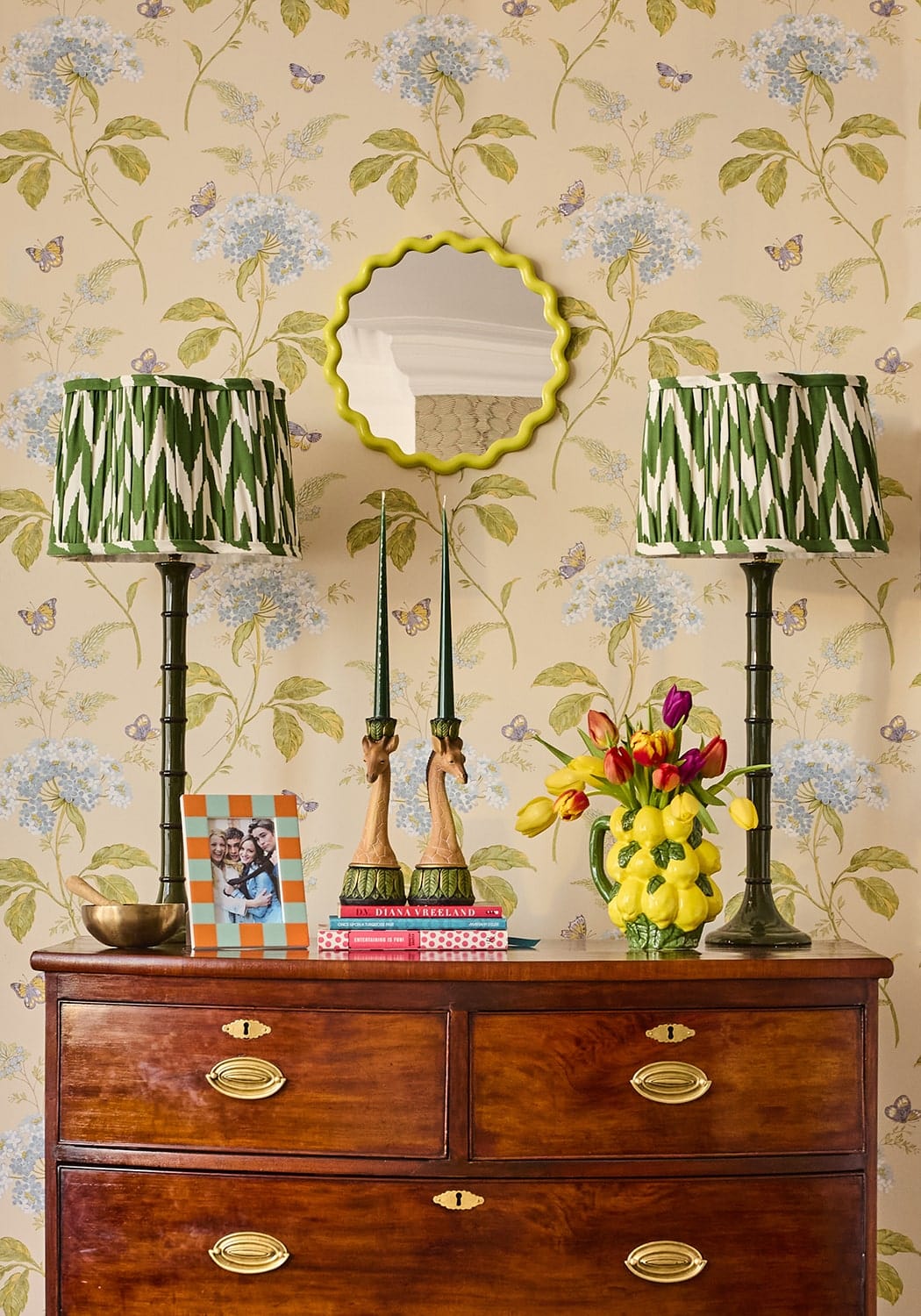 A pair of green and white zebra-striped lampshades with dark green bamboo-style bases alongside slender taper candles