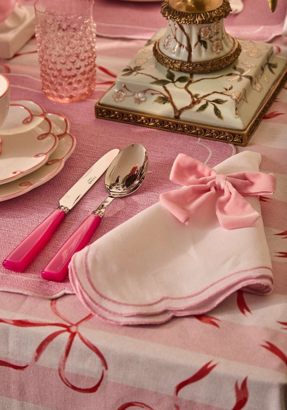 A delicate pink satin bow on a napkin paired with the aurora songbird taper candleholder left side