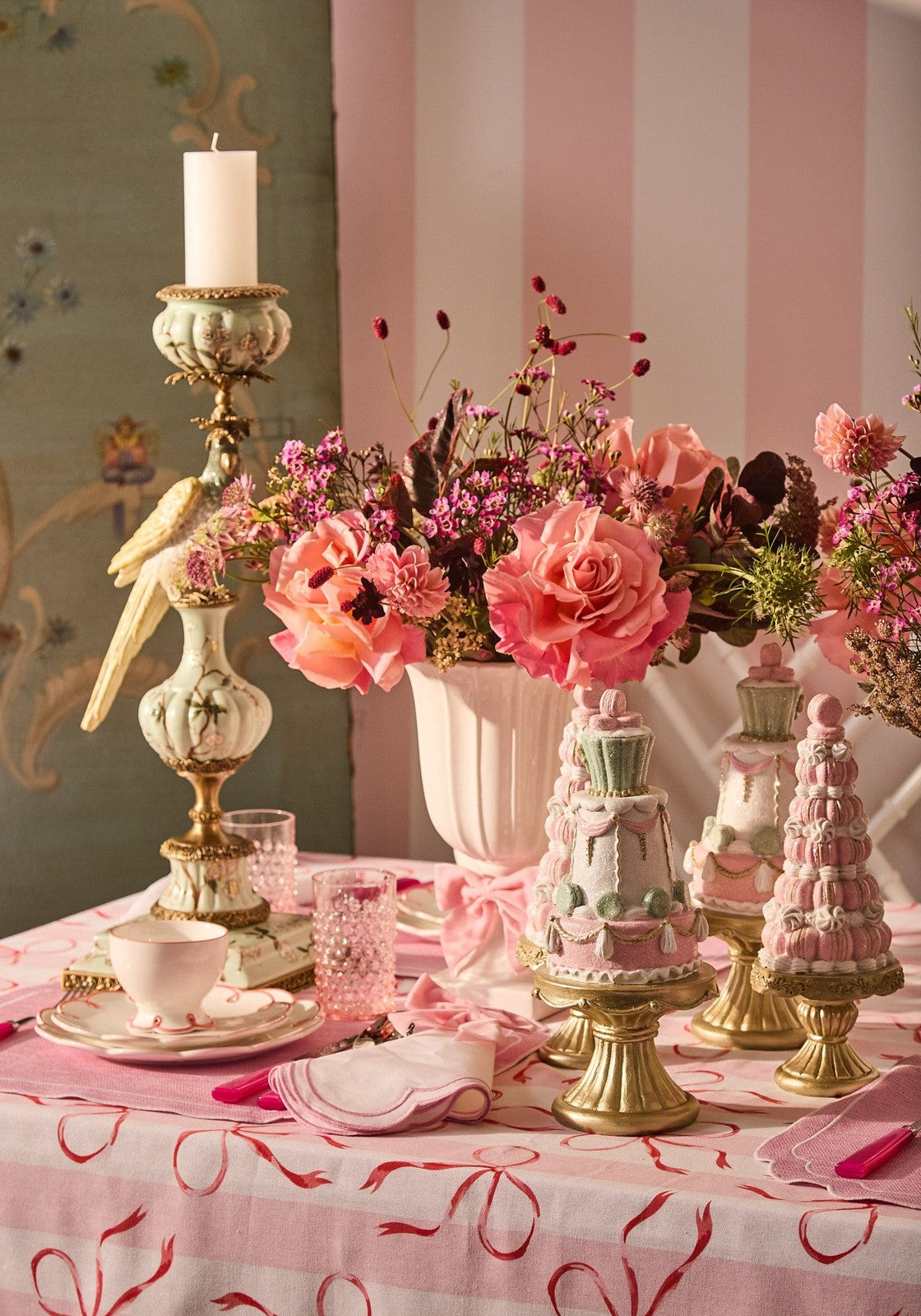 A delicate pink and white floral arrangement in a tall off-white Aurora Songbird taper candleholder left side