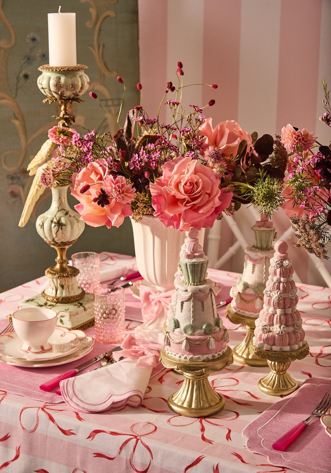 Pink and white macaron cake towers with gold bases shown next to the aurora songbird taper candleholder left side view