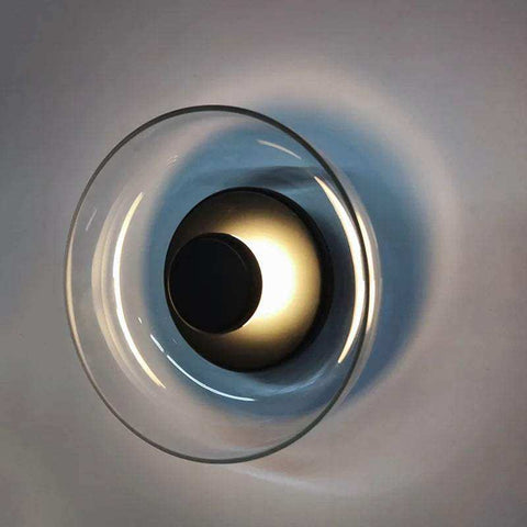 A modern aurora wall lamp with a circular glass design and an illuminated golden center wall lamp