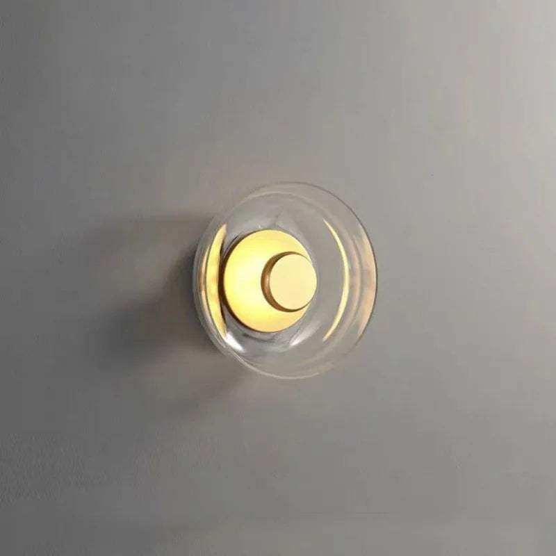 A modern minimalist aurora wall lamp with a clear glass dome and warm yellow circular led bulb wall lamp design