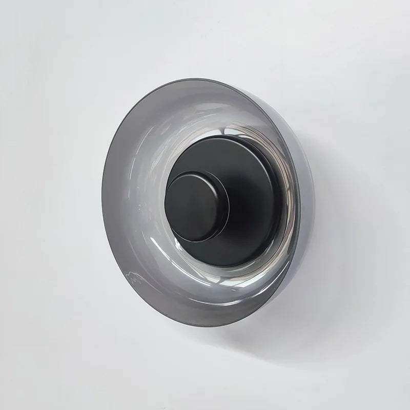 A sleek aurora wall lamp with a matte black base and translucent gray glass shade perfect as a modern wall lamp