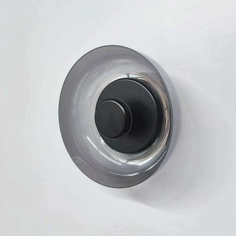 A sleek aurora wall lamp with a matte black base and translucent gray glass shade perfect as a modern wall lamp