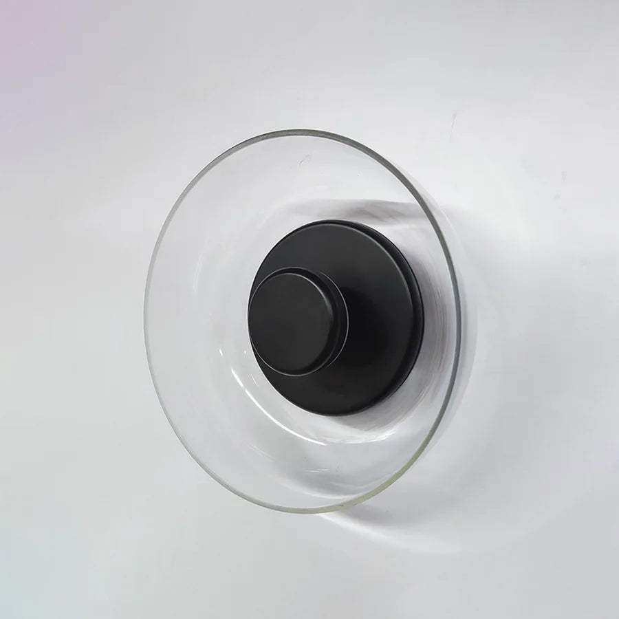 Clear glass vase with sleek black metal base as part of the modern aurora wall lamp design for stylish wall lighting