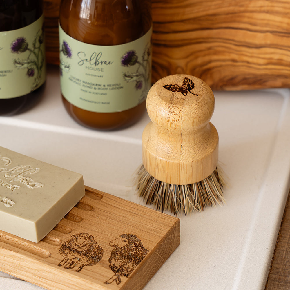 A natural wood bamboo pot brush with light brown coarse bristles and rounded handle from autumn acorns