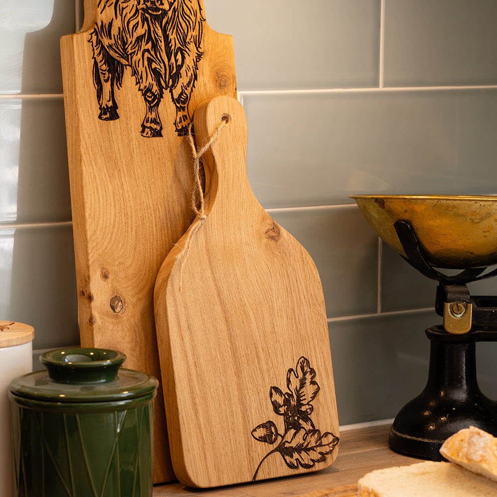 Light-colored wooden autumn acorns oak hanging paddle with hand-carved oak leaf design and natural wood handle
