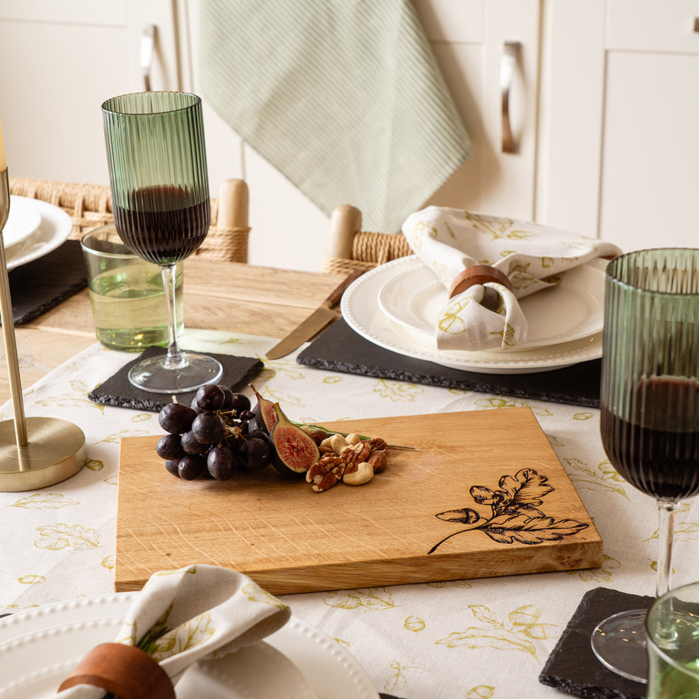 A light oak wooden cutting board with a dark engraved autumn leaf and acorn design perfect as an oak serving board
