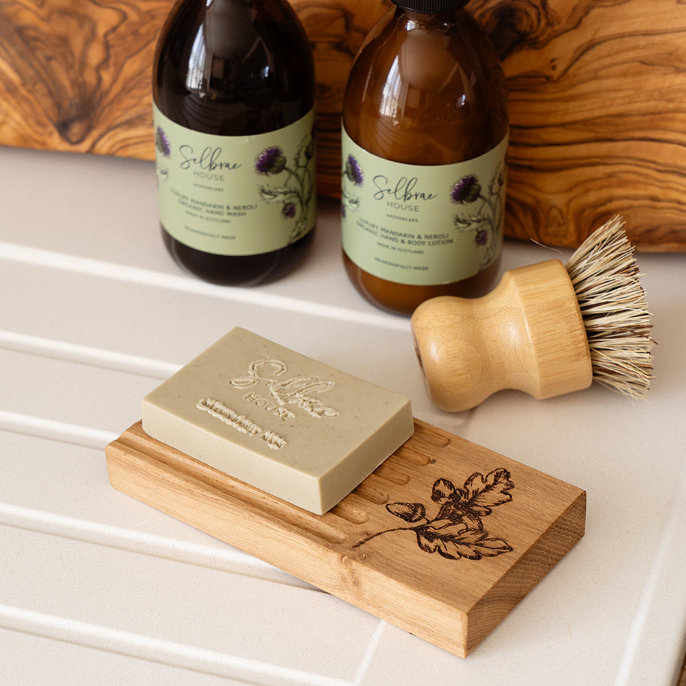 Light green oak soap bar resting on a wooden autumn acorns oak soap dish with engraved oak leaf design