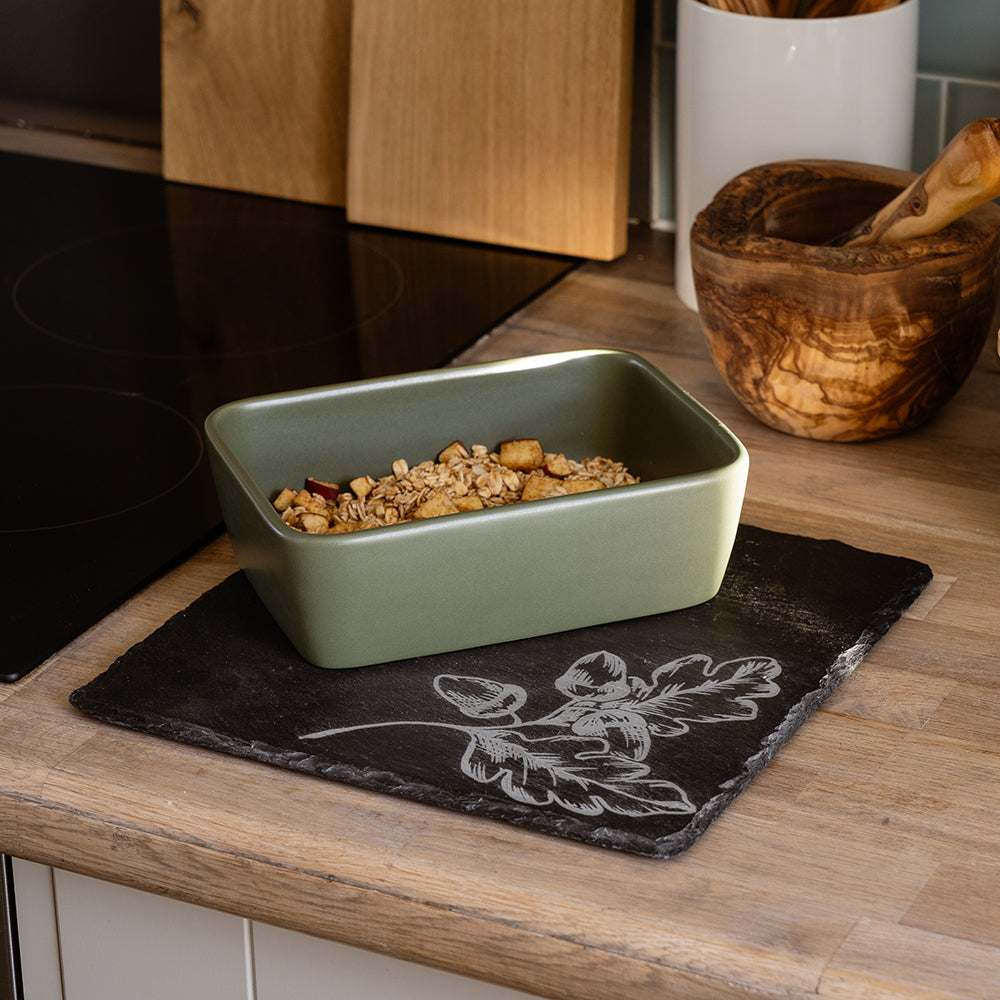 Olive green ceramic rectangular baking dish on an autumn acorns slate pot stand for stylish kitchen use
