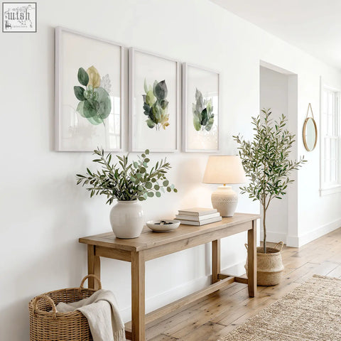 White ceramic vase with green eucalyptus branches next to autumn art botanical leaf three prints in green and gold tones