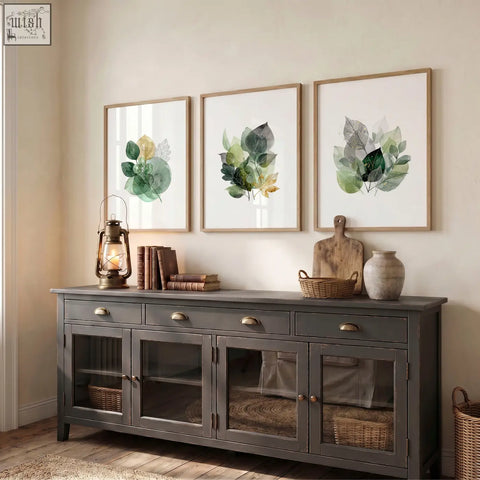Dark gray wooden sideboard with glass paneled doors and brass handles complements autumn art botanical leaf three prints wall decor