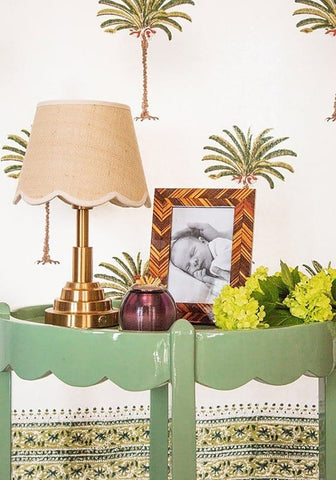 A brass table lamp with a beige scalloped fabric shade next to an autumn bark photo frame 6x4 inches