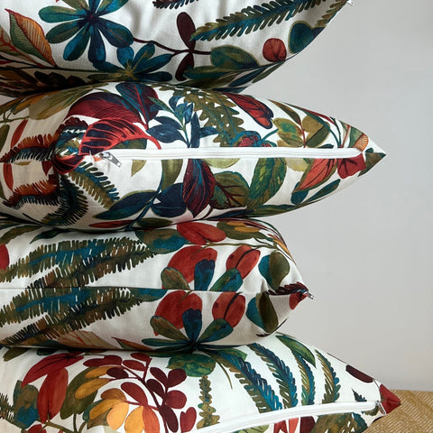 Stack of autumn leaves cotton throw cushions with vibrant red green and blue botanical print on white background