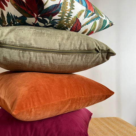 Stacked autumn leaves cotton throw cushions in olive orange and magenta with a vibrant botanical leaves cotton throw top pillow