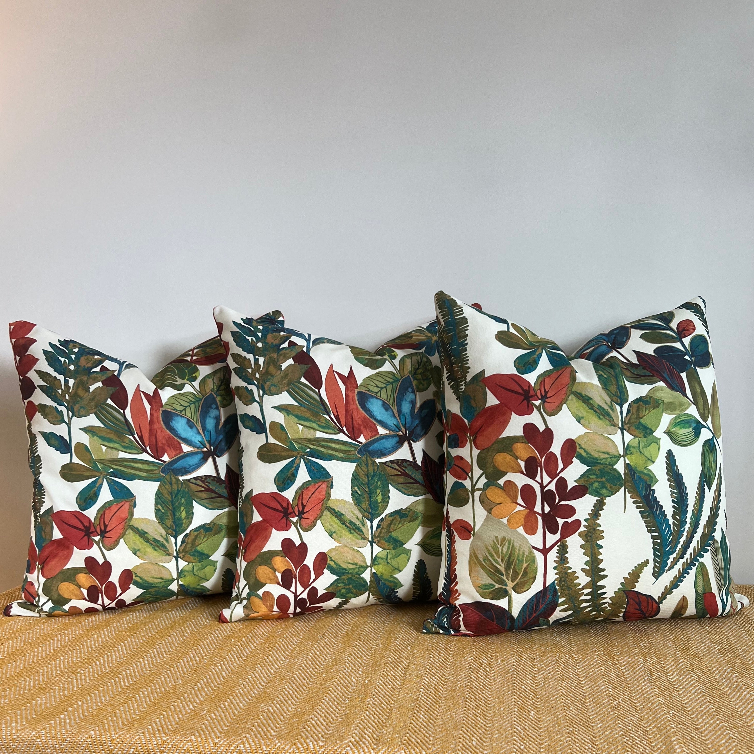Three rectangular cotton throw cushions with vibrant autumn leaves cotton print in red blue green and orange on white