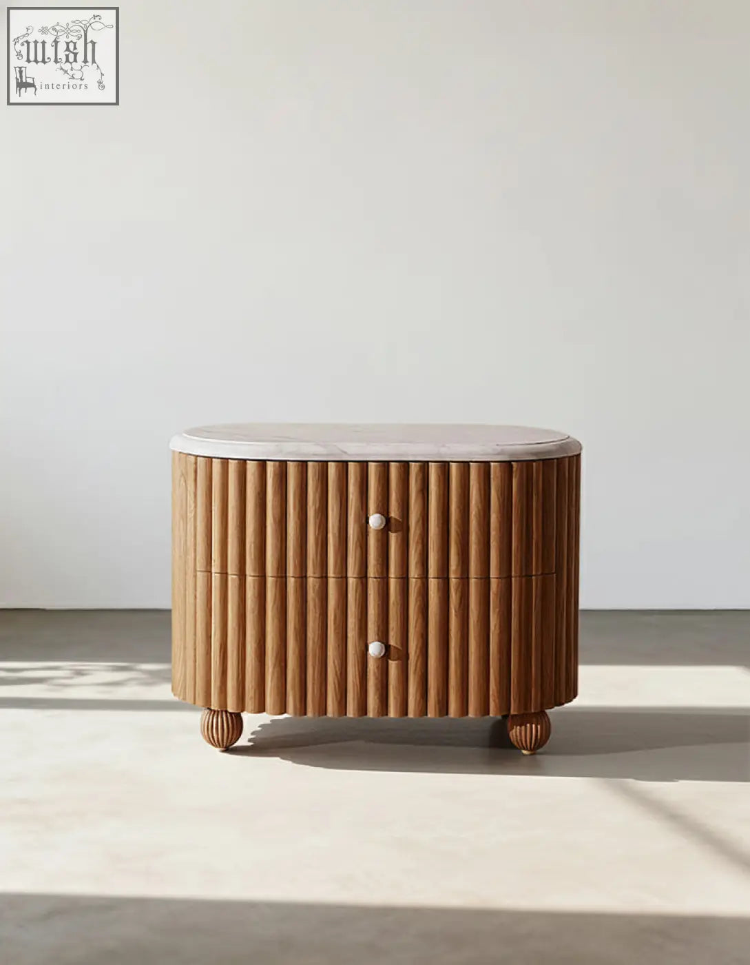 A modern wooden bedside table with vertical slats white marble top and rounded ball feet in rounded rectangle style