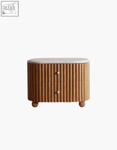 A sleek oval-shaped wooden bedside table with vertical slats, smooth white marble top, and rounded rectangle rounded feet