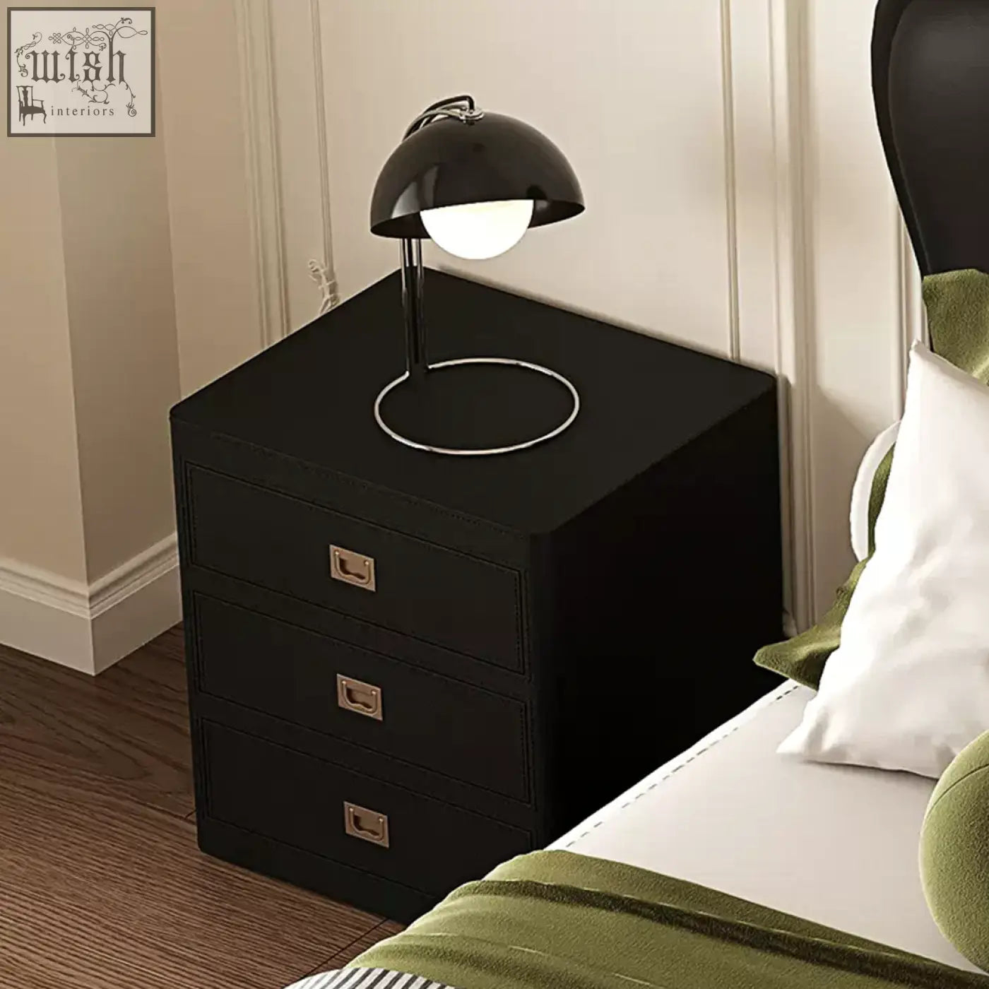 Black aveline bedside table with three drawers and brass handles topped by a sleek black dome lamp