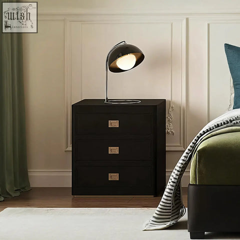 Black aveline bedside table with three drawers and brass handles featuring a sleek modern design
