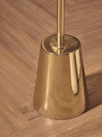 Brass-finished toilet brush holder with sleek conical design and polished gold base complementing black marble effect decor