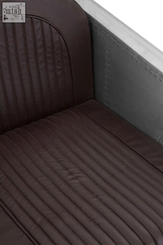 Avro armchair with dark brown faux leather ribbed upholstery and riveted metal frame inspired by airplane seats