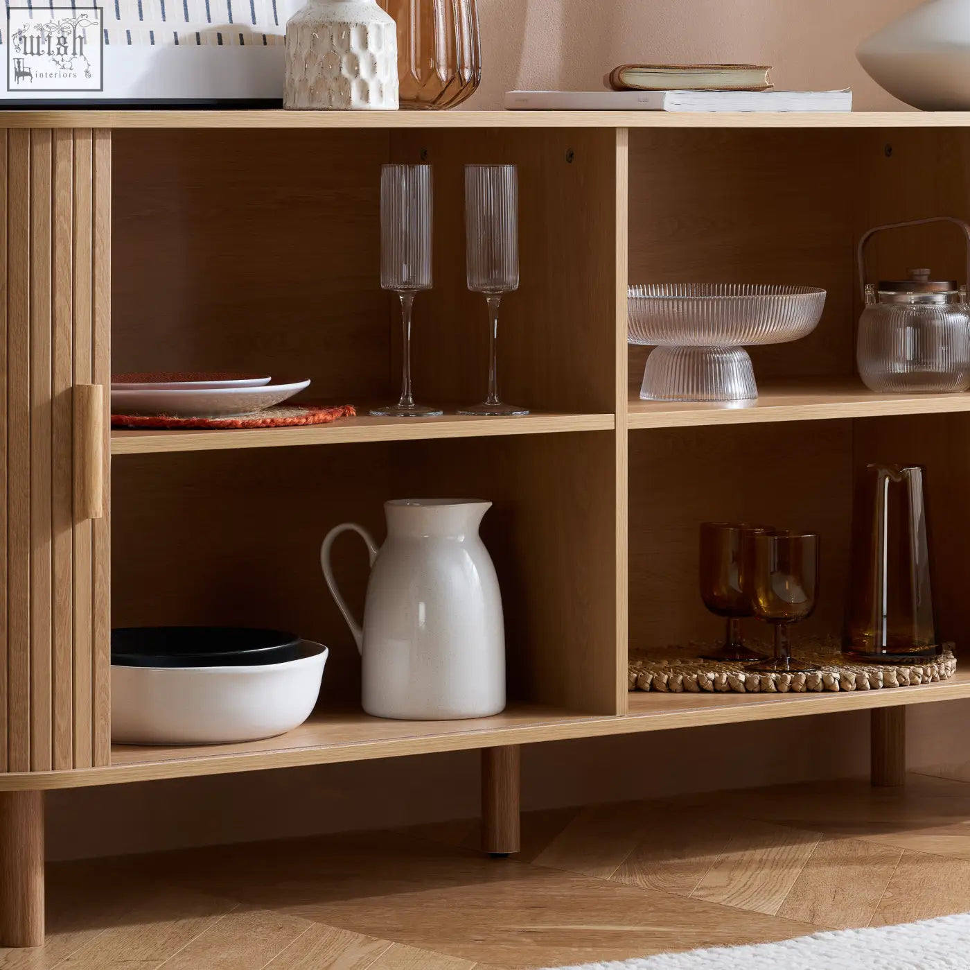 A white ceramic pitcher with a glossy finish sits on the wooden shelf of the axel 2 door fluted dining sideboard