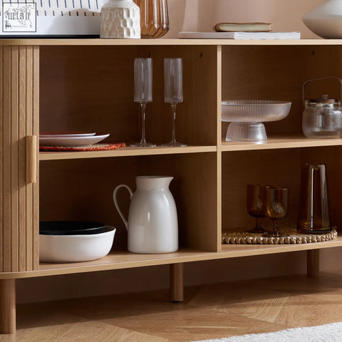 A white ceramic pitcher with a glossy finish sits on the wooden shelf of the axel 2 door fluted dining sideboard