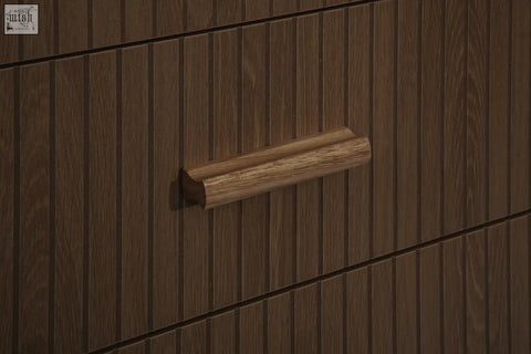 A sleek light brown wooden drawer handle with a smooth rounded design on the axel 6 drawer chest from the fluted bedroom range