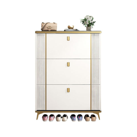 White ayling shoe storage cabinet with gold stripes handles topped with beige handbag and white flowers vase