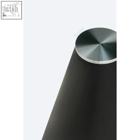 Black conical speaker with brushed metallic top placed on an azalea round clear glass dining table