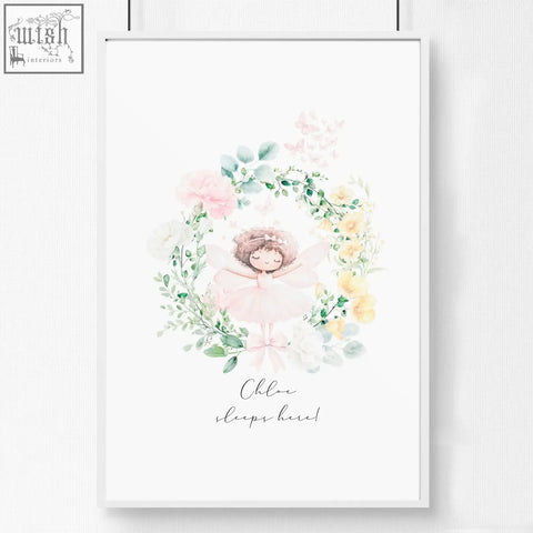 A delicate watercolor wall art print of a sleeping ballerina with pink flowers in a white frame for baby’s room