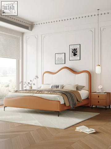 A sleek tan leather badham king size bed with a curved headboard and white upholstered paneling